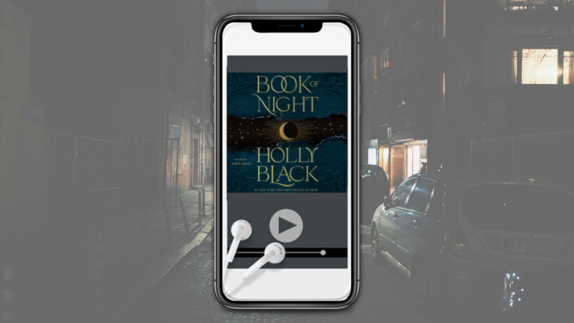 Book of Night cover on an iPhone plus headphones over a dark city street background