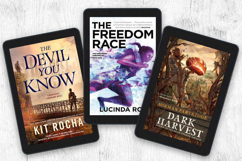 Tablets showing the following covers in a fan array: The Devil You Know by Kit Rocha / The Freedom Race by Lucinda Roy / Dark Harvest by Norman Partridge