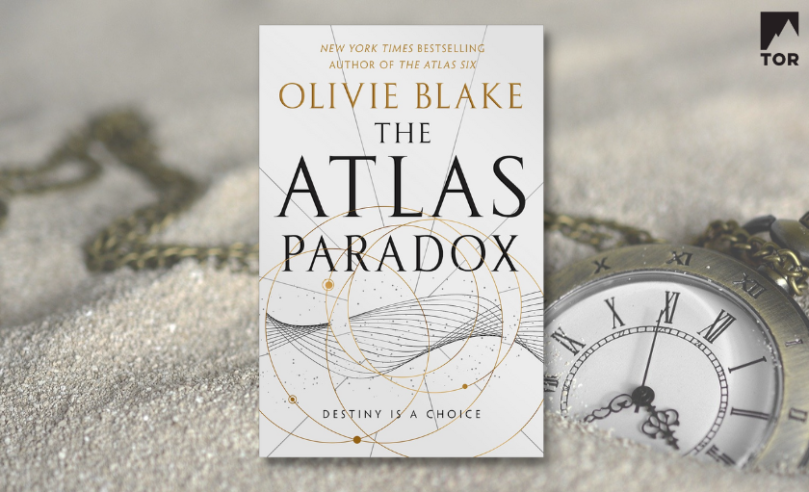 Foreground: The Atlas Paradox by Olivie Blake / Background: Sand with pocketwatch and chain partially buried