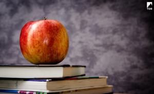 apple on top of some books with gray background
