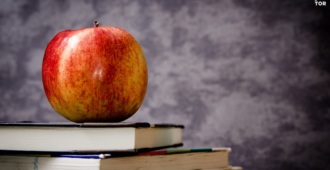 apple on top of some books with gray background