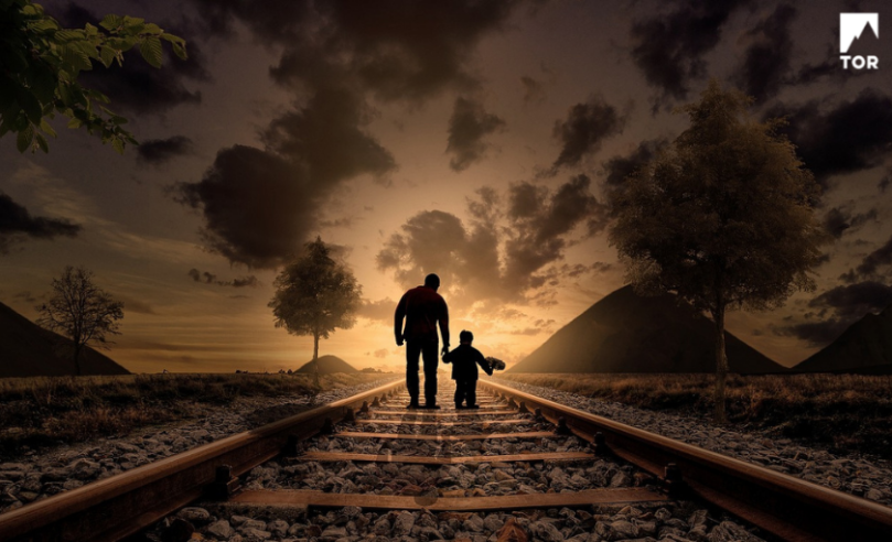shadow of parent and child walking into the sunset along abandoned train tracks