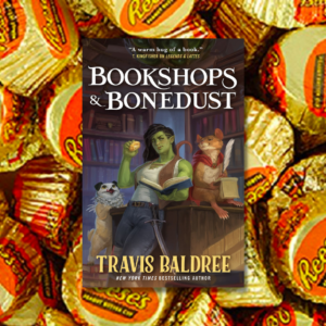 Bookshops & bonedust by travis baldree in front of a golden array of wrapped reese's peanut butter cups