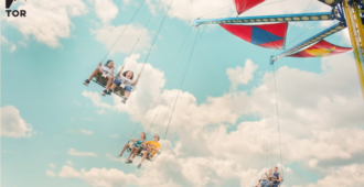 low angle photograph of a carnival tiltawhirl swingset with people swinging next to soft white clouds